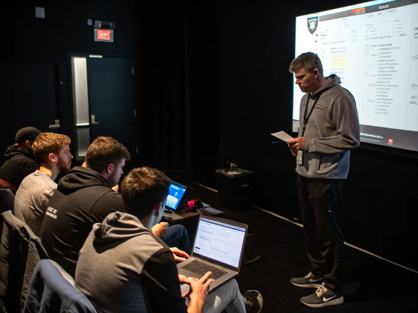 An image of a diverse group of gamers intensely focused during a training session, with coaches providing guidance in a modern gaming facility. The scene should convey a sense of dedication and teamwork.